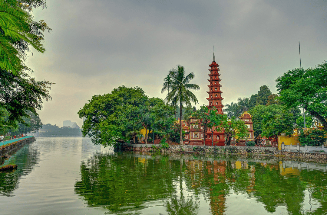 Tran Quoc Pagoda, the oldest Buddhist temple in Hanoi, Vietnam, situated on a small island in West Lake, surrounded by lush greenery and calm waters.